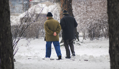 Two senior friends walking at the park during winter