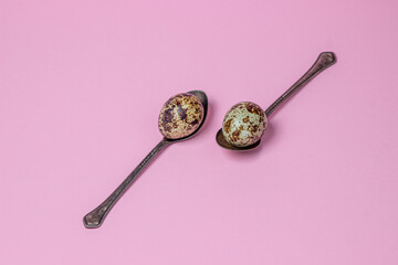 Quail eggs on a pink background. Healthy food. Quail eggs lie on teaspoons