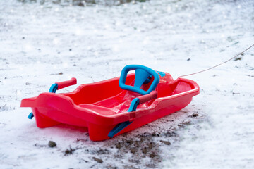 Red plastic sled on snowy ground in winter forest