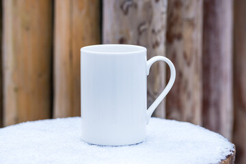 White porcelain coffee cup, mug on outdoor frozen snow