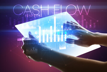 Hand holding futuristic tablet with CASH FLOW inscription above, modern business concept