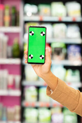 Hand of female shopaholic holding smartphone with green e-coupon on screen