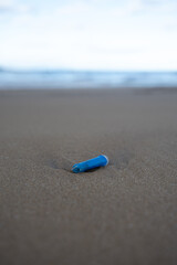 A shot of a piece of plastic on a sandy beach - plastic pollution