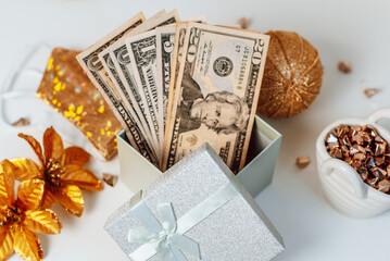 dollar bills in a gift box as a christmas present next to christmas accessories and a protective face mask