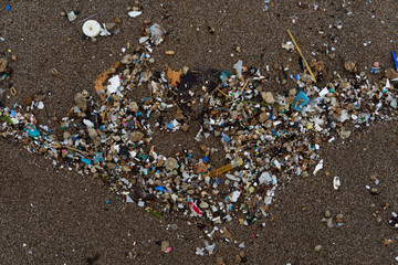 A top view of plastic and microplastic on a sandy beach - plastic pollution