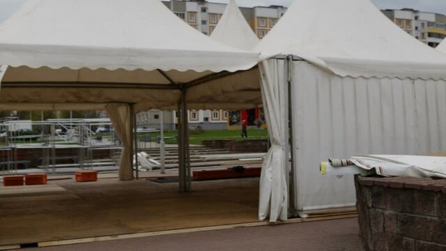 Mobile tent on an aluminum frame on the square in the residential quarter. Outdoor, real time, natural light, camera movement from right to left