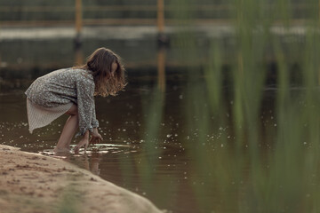 a girl plays in the river circles on the water drives her palms through the water there is a wave
