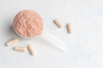 Scoop of whey or soy protein isolate, white capsules of amino acids and creatine, bodybuilding food...