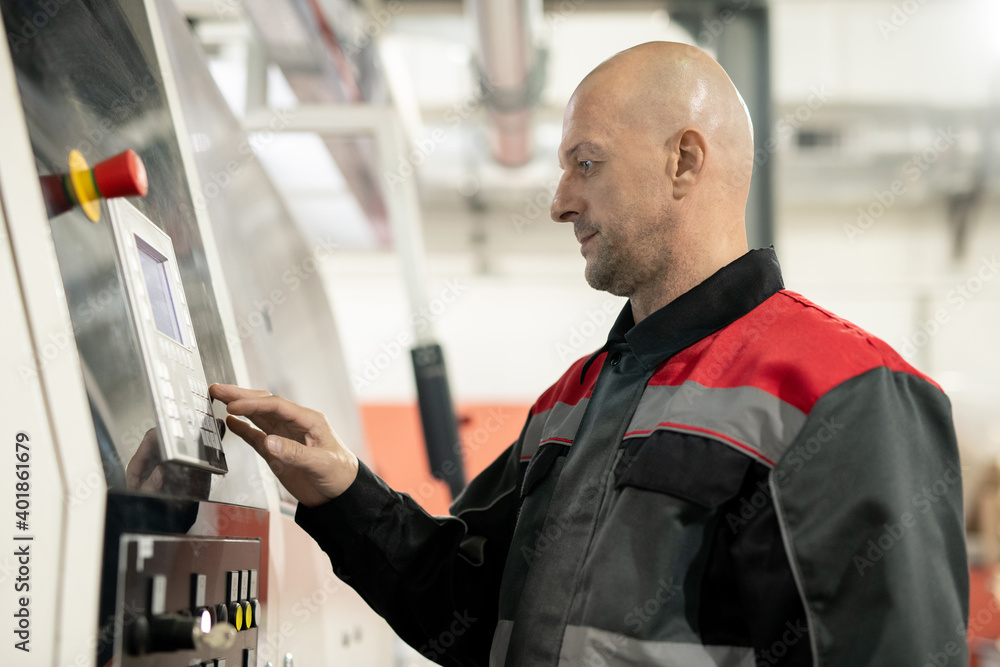 Poster Mature worker of polymer processing factory pressing button on control panel