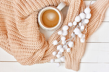 Winter background with cup of cappuccino, knitted sweater and fluffy branch.