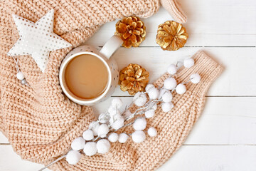 Fototapeta na wymiar Winter background with cup of cappuccino, knitted sweater, fluffy branch, white star and cones.