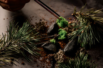 male hand holds ingredient with tweezers and adds it to modern molecular cuisine dish