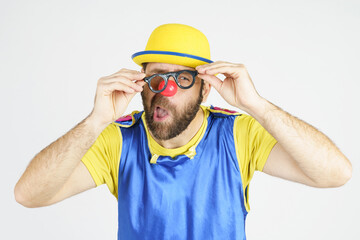 A clown in a bright blue and yellow suit adjusts his glasses