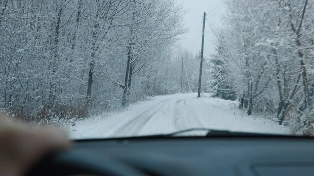 Person driving in snowy winter village POV