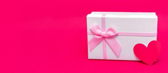 Gift box and card in form of heart on pink-red background. Give gifts with love on Valentine's Day, Christmas and birthday. Delicate white packaging with ribbons. Surprise your loved. Happy holiday