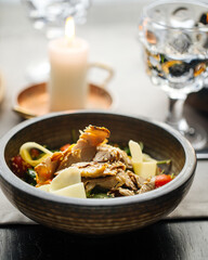 Closeup on a bowl with beef salad with vegetables and cheese