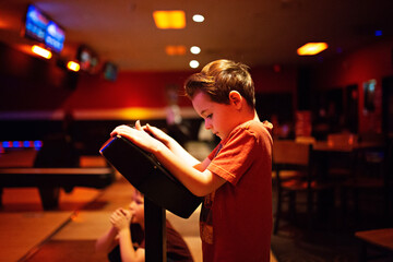 boy in red shirt bowling with his family