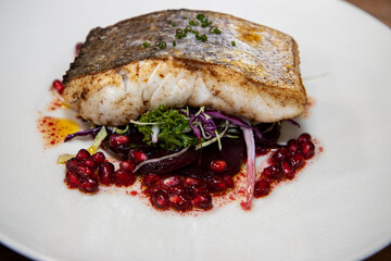 A delicious plate of fish Hake with winter salad and pomegranate