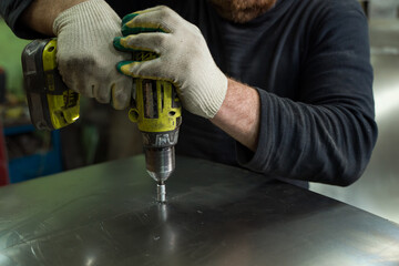 Man Works in Auto Workshop with Cordless Screwdriver
