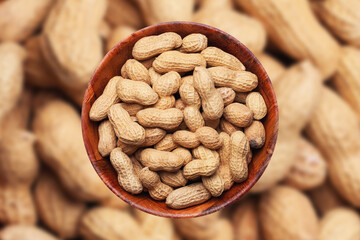 Peanuts background. Vegetarian diet food. Nuts in shells inside round wooden bowl isolated. Snacks in a bowl. Healthy party snack. Nut shells pattern.