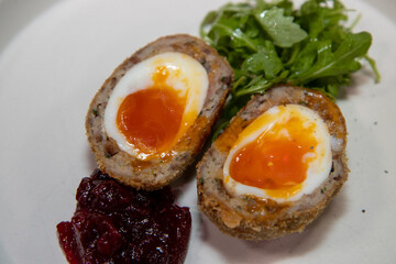 A delicious home made scotch egg on a white plate with salad