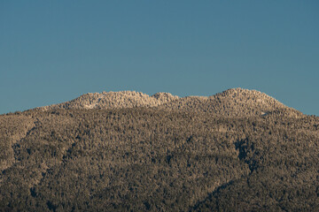 mountain peaks and slopes covered with a thin layer of snow under blue sky on a sunny morning 