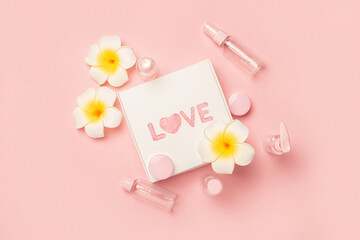 Obraz premium Empty tubes for cosmetics, flowers and a gift box with the text Love on a pastel pink background. Flat lay, top view. Banner