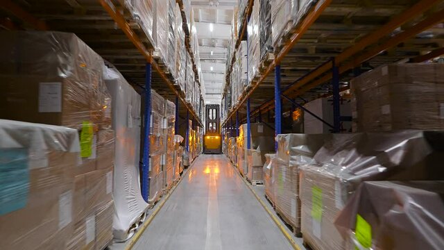 Equipment components are stored on racks. The yellow forklift drives through the rows.
