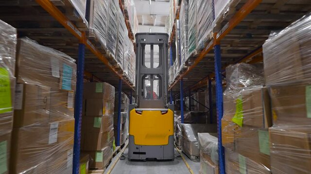 Equipment components are stored on racks. The yellow forklift drives through the rows.