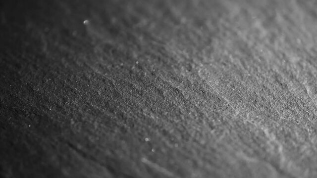 4K Texture of dark gray graphite or shale stone background. Elegant lighting. Rotating macro extreme close up of schist plate. Graphic and highly detailed natural backdrop of material surface.