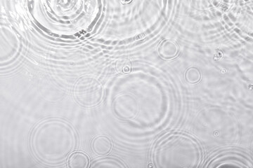 A top view closeup of waterdrops falling on the surface and forming a circular shape