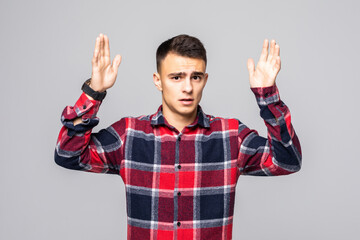 Naklejka premium Portrait of young handsome man with raised hands against grey background