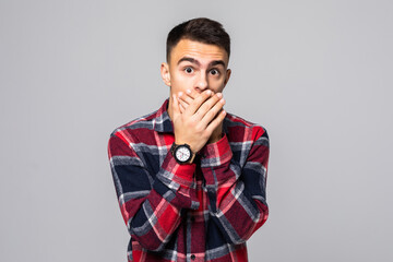 Handsome man closes his mouth in shock, isolated on white background