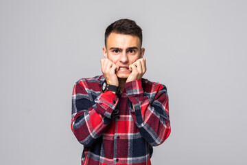 Obraz premium Young scared man in white t-shirt over gray background