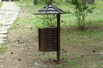 natural wooden trash bin with a roof beside the pathway in the forest or park