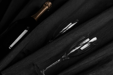 Naklejka premium Two champagne glasses and bottle on black background. Celebrating New Year, Valentine day.