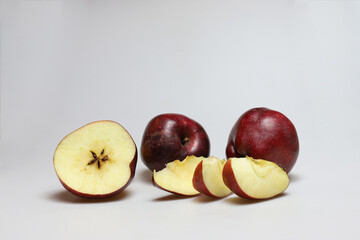 Two whole and one half apple fruits with apple slices on a white background