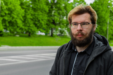 Fototapeta premium bearded man with mustache Caucasian white face portrait of middle adult person outdoor on the street with green trees spring background scenic view