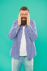 stressed caucasian guy with beard and mustache suffer from headache on blue background, pain
