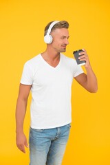 Happy handsome man listen to music in earphones drinking takeaway coffee cup, break time