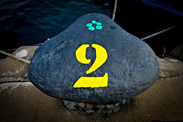 Number 2, two, a bold yellow digit on a black harbor bollard.