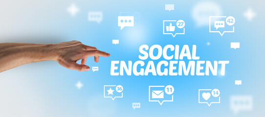 Close-Up of cropped hand pointing at SOCIAL ENGAGEMENT inscription, social networking concept