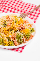 Ready-made Italian pasta with hearts in a white plate on a checkered white-red tablecloth and sprinkled with grated cheese. Valentine's day dinner.