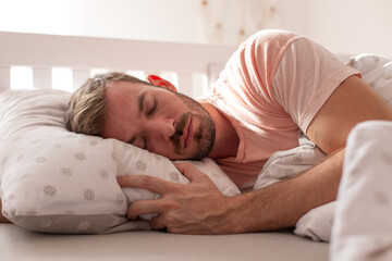 The handsome man is sleeping in the bed.