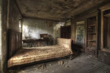 Foto op Plexiglas Oude verlaten gebouwen Een slaapkamer van een verlaten huis met vuile muren en kapotte meubels