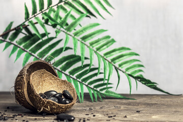Spa - composition. Stones for body massage on a wooden table. Green leaves in the background, blur, copy space.