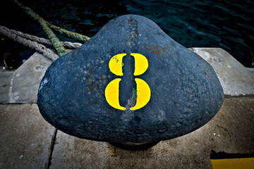 Number 8, eight, a yellow digit on a black harbor bollard.