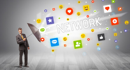 Handsome businessman defending with umbrella from NETWORK inscription, social networking concept