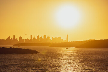 Beautiful evening sunset shot of the Sydney Harbour with the Sydney skyline in the background, seen from Fairfax Lookout at North Head Sanctuary. Shot in December 2020. Boats cruising in harbour.