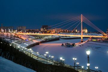 Fototapeta na wymiar Pedestrian bridge on the embankment in Tyumen, Russia, at night, in winter
